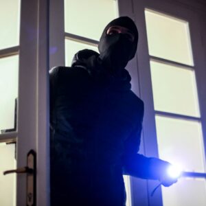 Masked intruder coming through a door