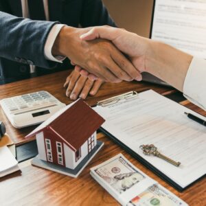 Closeup of two people shaking hands over a desk with real estate documents