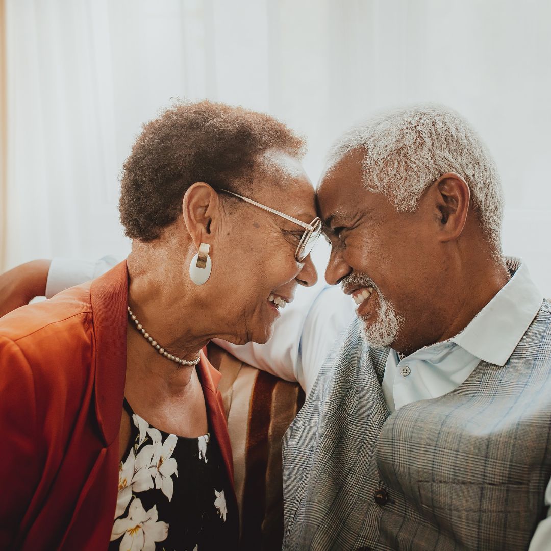 an older couple touching their foreheads together