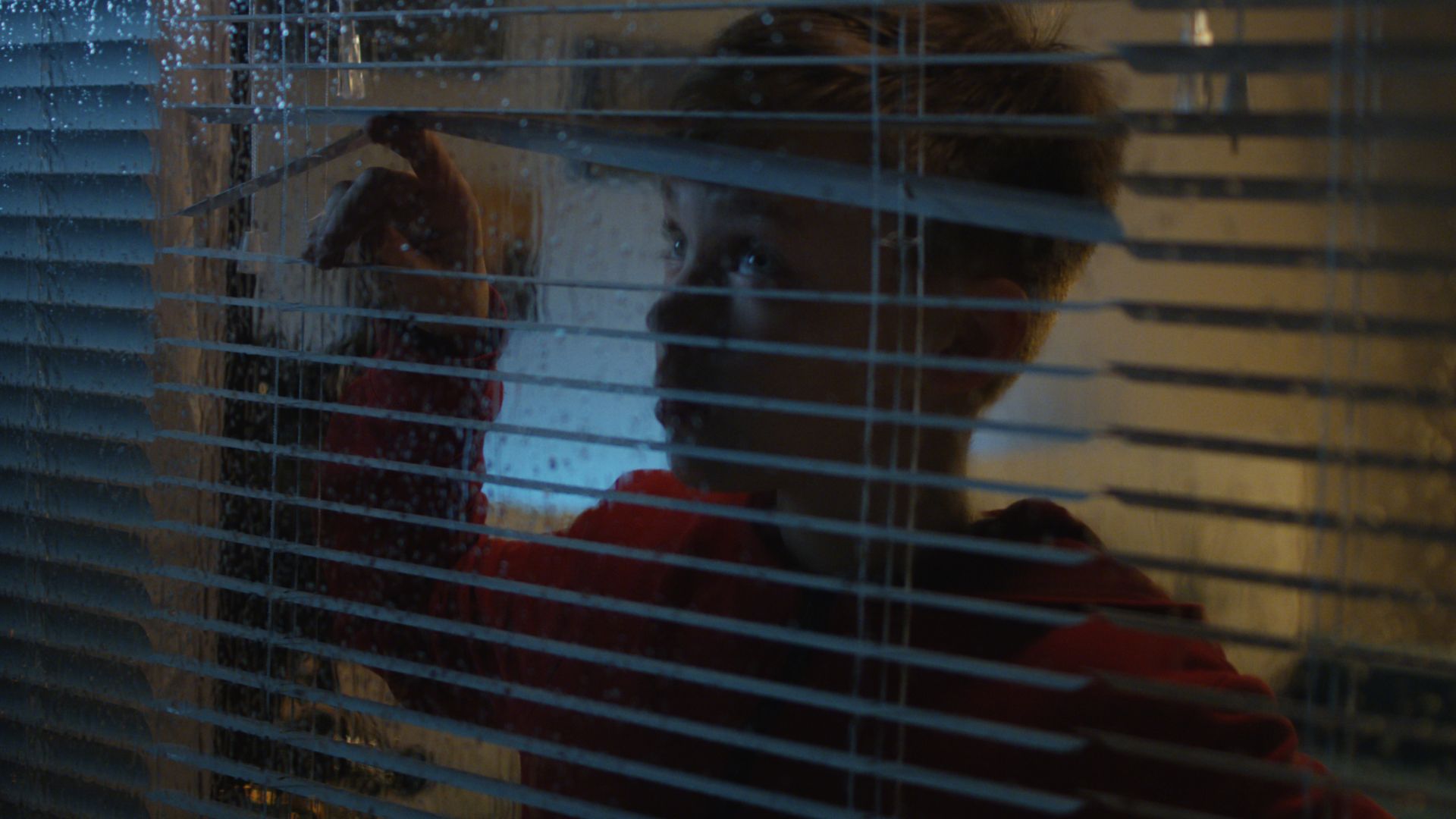 child peaking through blinds