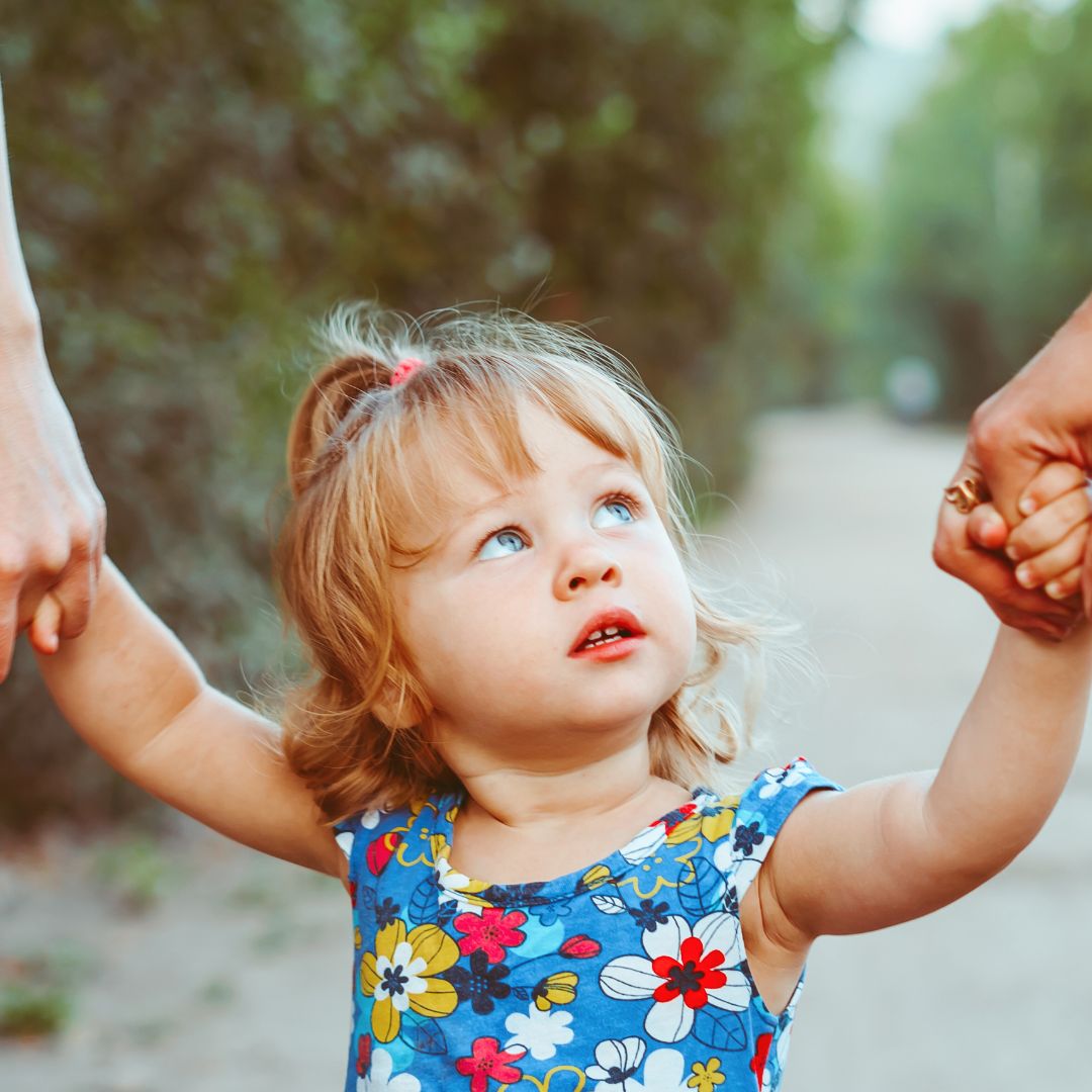 A little girl holding hands with her parents