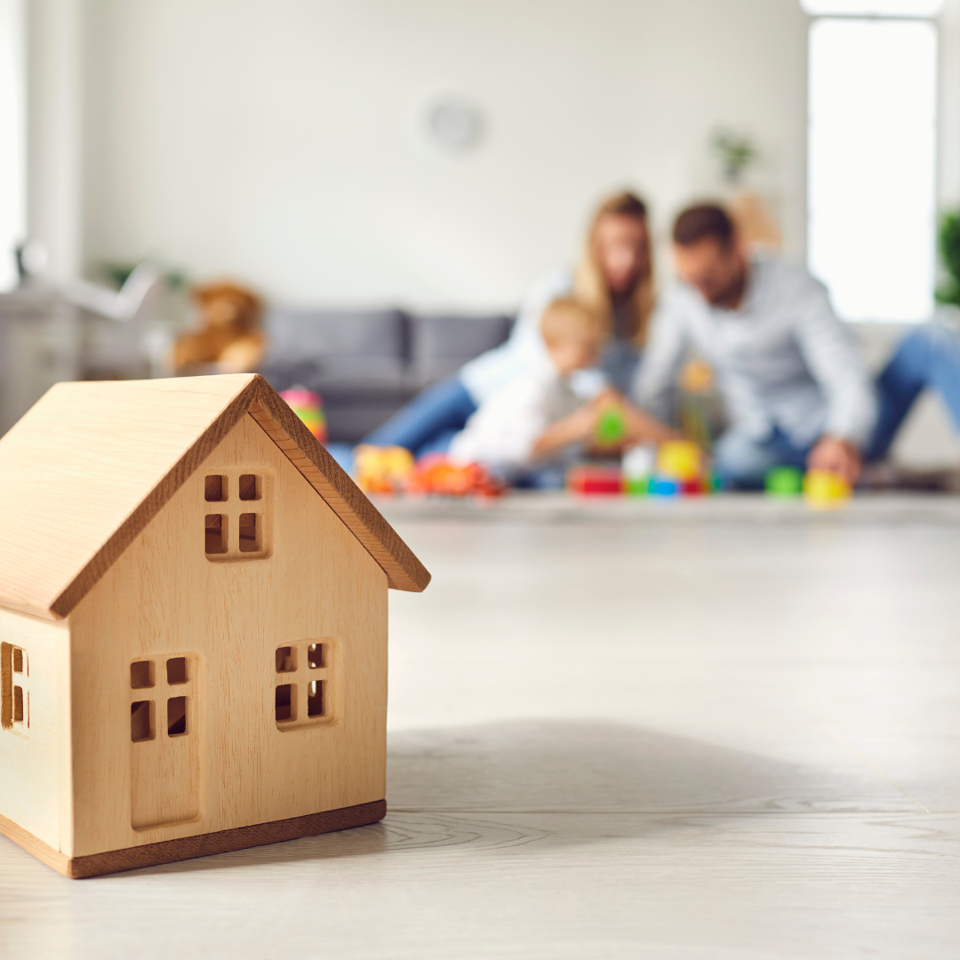 Wooden model house in front of a family.