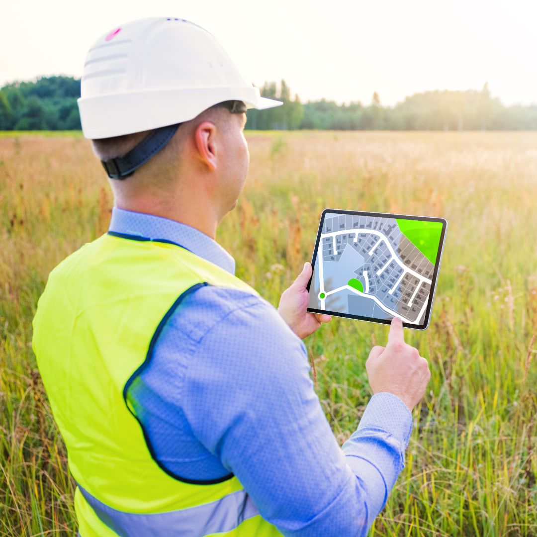 Man in a hard hat looking at a tablet while plotting space for something.