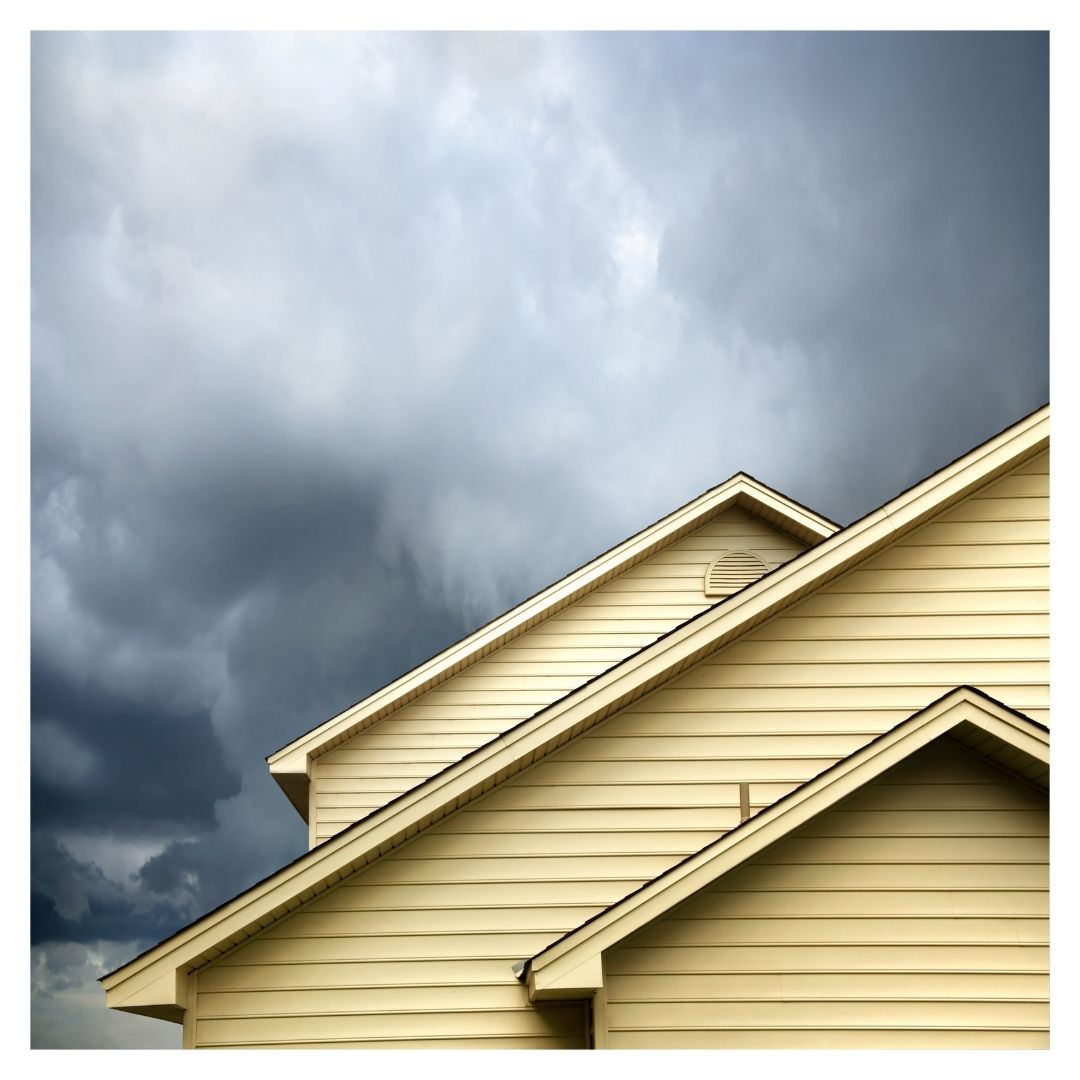 The roof of a house with storm clouds in the background