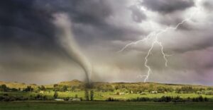 Tornado and lightning over rural landscape with dark clouds