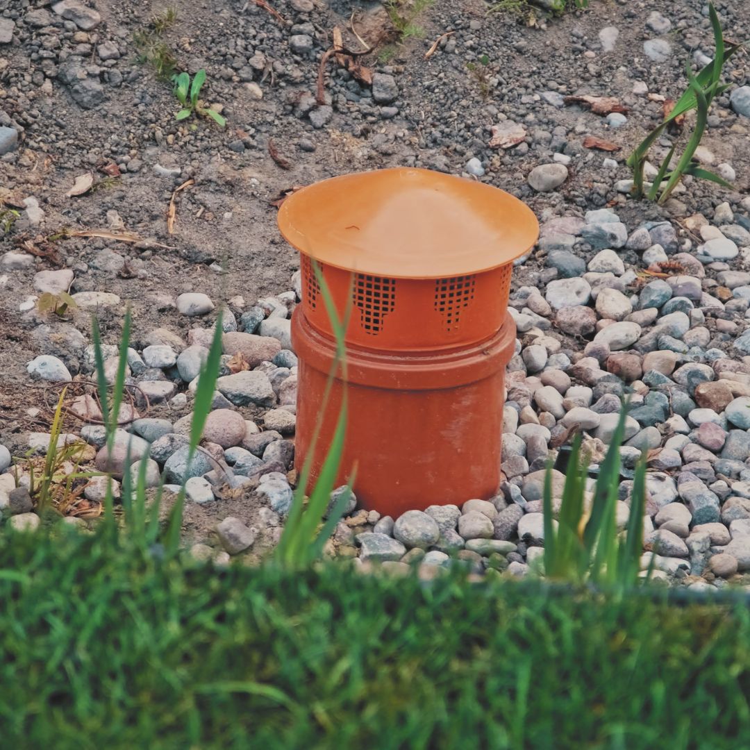Orange drain pipe surrounded by rocks and grass
