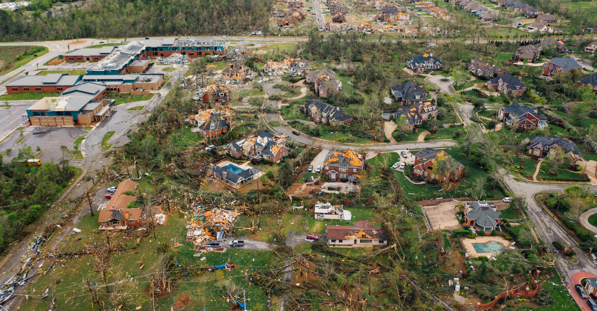 Tornado-damaged neighborhood with destroyed homes and uprooted trees