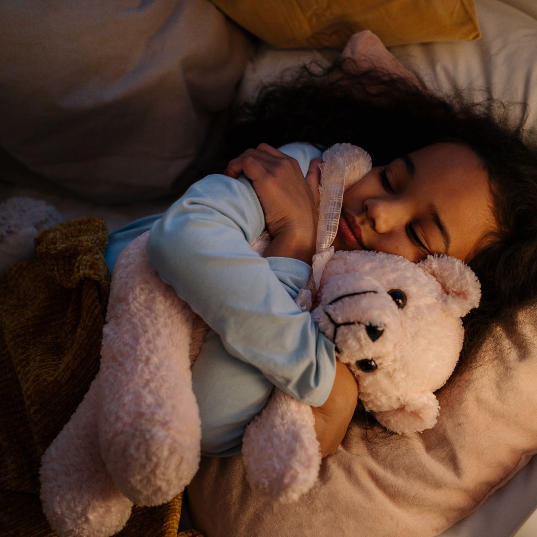 girl laying down with her stuffed animal