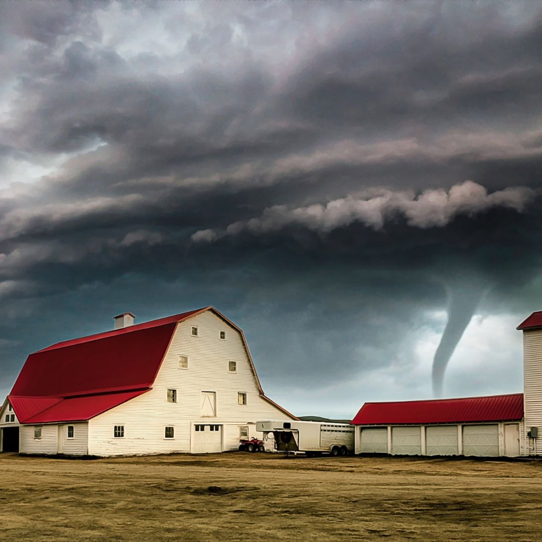 tornado behind a large red and white barn