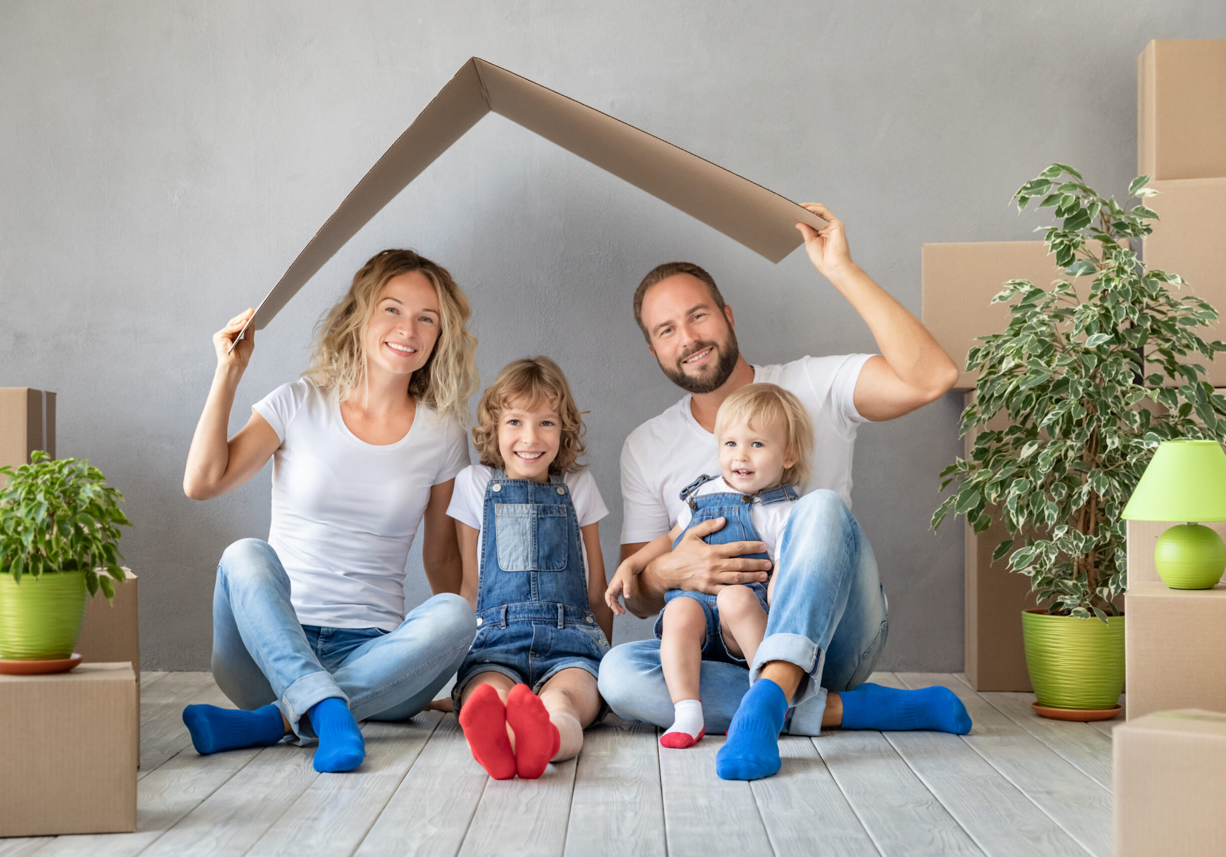 Happy family with two kids playing into new home. Father, mother and children having fun together. Moving house day and real estate concept